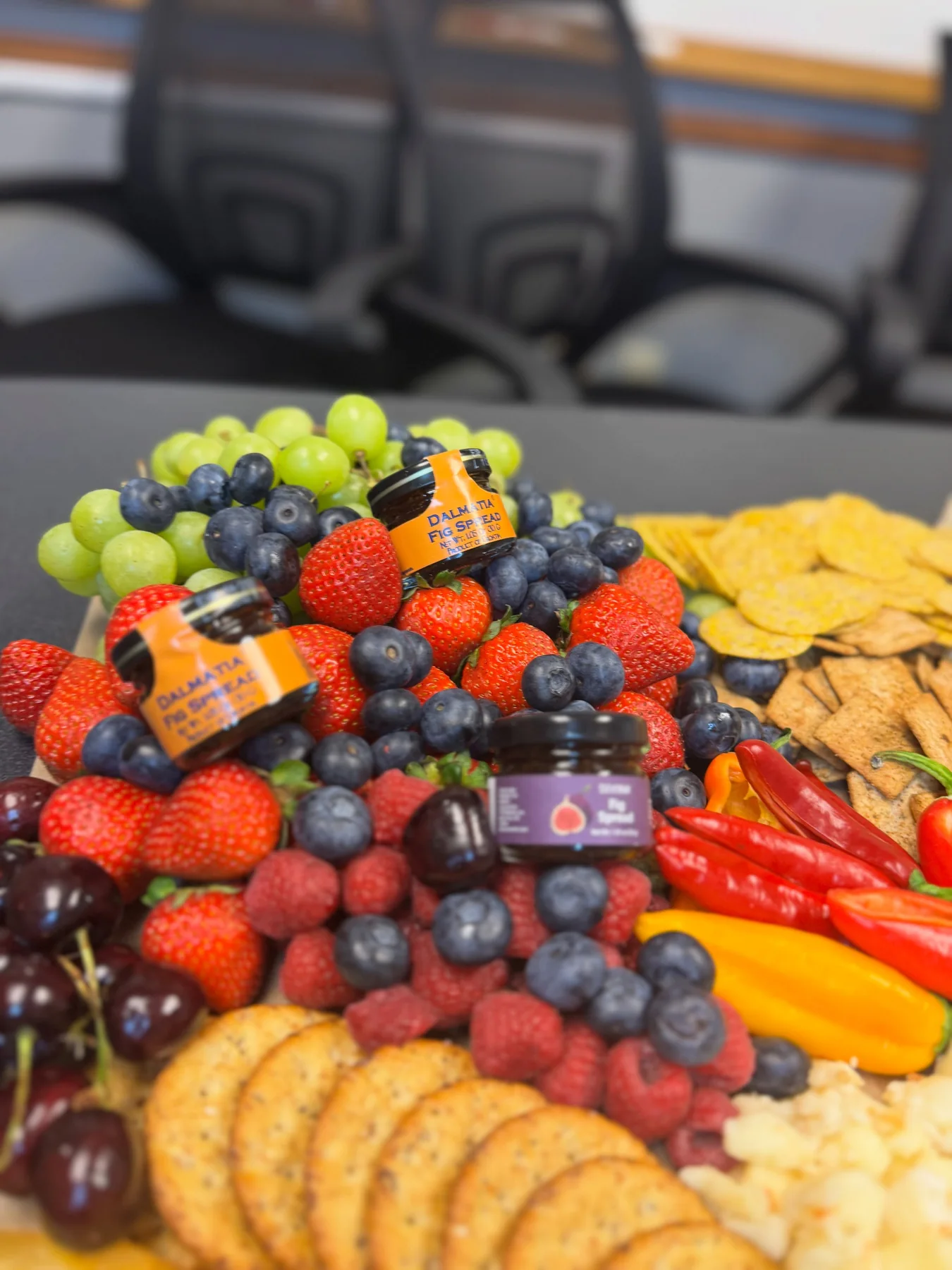 Close-up of strawberries, blueberries, peppers, crackers, and fig spreads