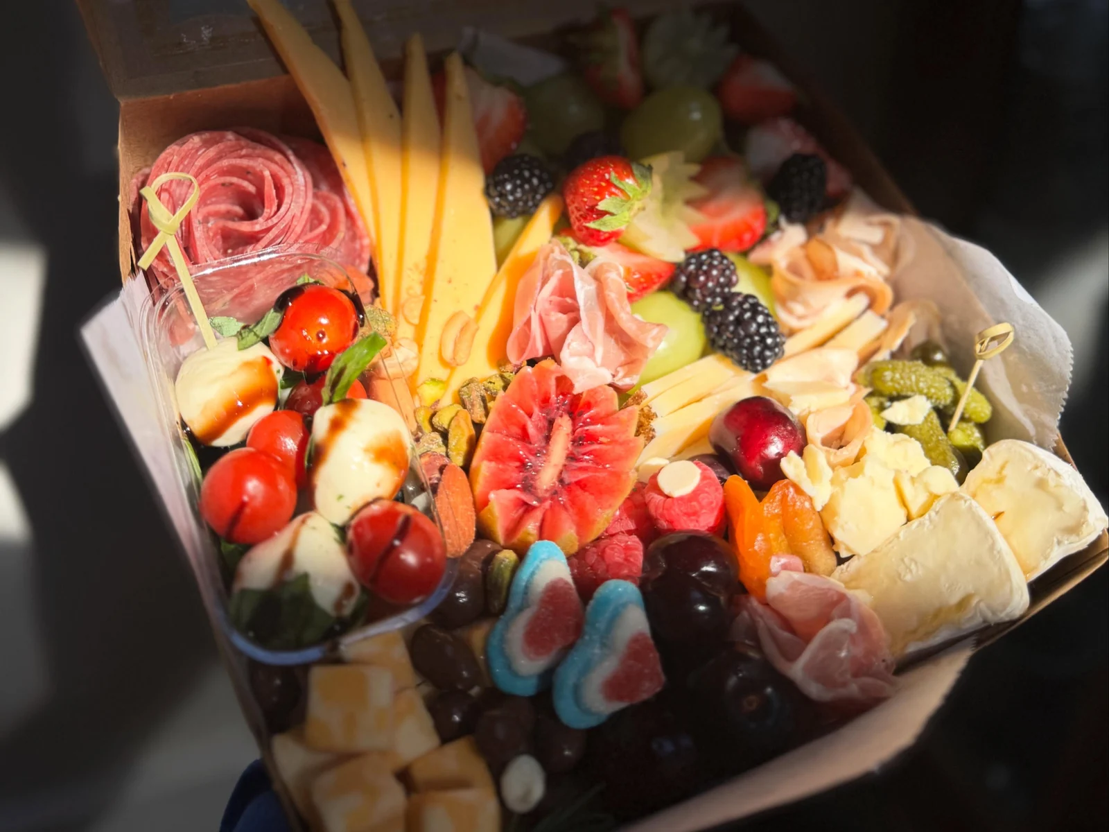 Colorful sweet and savory charcuterie box with fruit, cheeses, meats, and chocolates